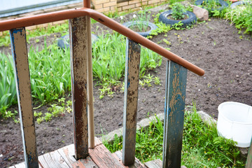 Handrails of an old porch against the background of a flowerbed.