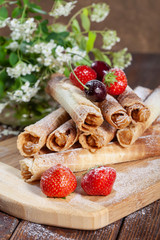 Cream wafer rolls decorated with cherries and strawberries, homemade cakes