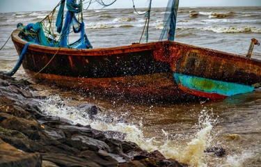 old fishing boat anchored on the seashore.