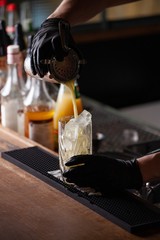 bar tender with gloves preparing mixed drink cocktail