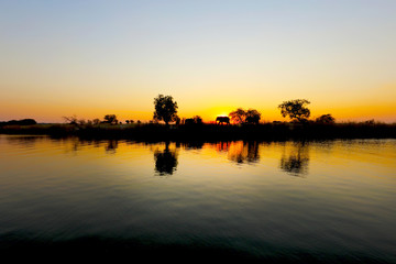 Obraz premium Sunset in Africa with an elephant in the horizon along the Chobe River in Botswana.