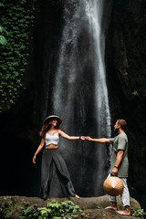 A couple in love on a waterfall. Honeymoon trip. Happy couple on the island of Bali. Beautiful couple travels the world. Travel to Indonesia. Happy couple on vacation.  Wedding trip. Copy space