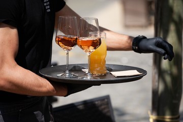 restaurant worker with gloves delivering drinks