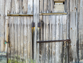 detailed view of an old wooden barn wall and closed doors with rusty padlocks