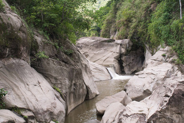 Huge rock formations formed by streams of water and a small waterfall.