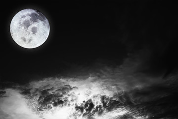 Black and white image of blurry cosmic clouds and bright full moon with stars on dark sky background. Image of moon furnished by NASA.