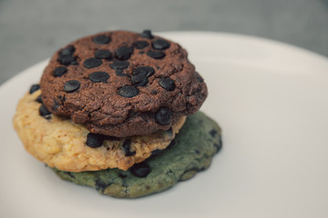 various chocolate cookies on white plate on grey cement surface
