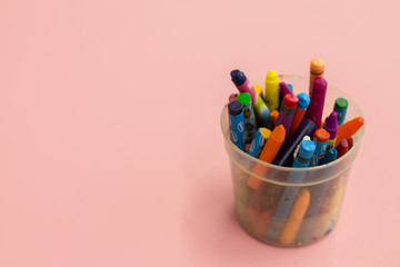 Jar with crayons on a pink background. Children's background.
