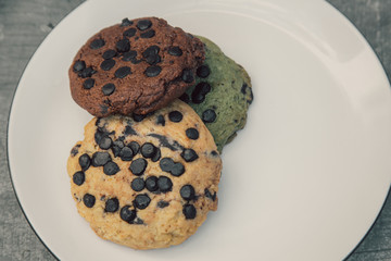 various chocolate cookies on white plate on grey cement surface