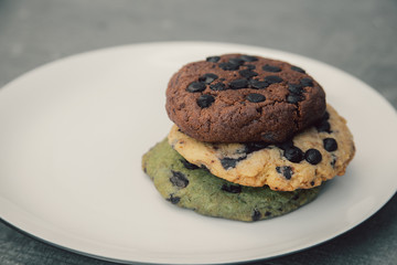 various chocolate cookies on white plate on grey cement surface