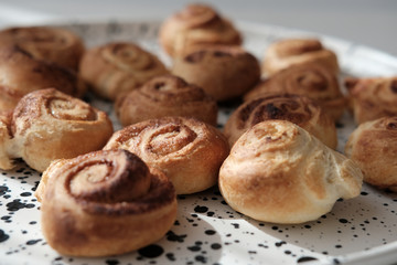 homemade cinnamon rolls or buns on a plate. close up view. selective focus. cinnamon swirls under sunlight. cooking at home concept. summer party dessert
