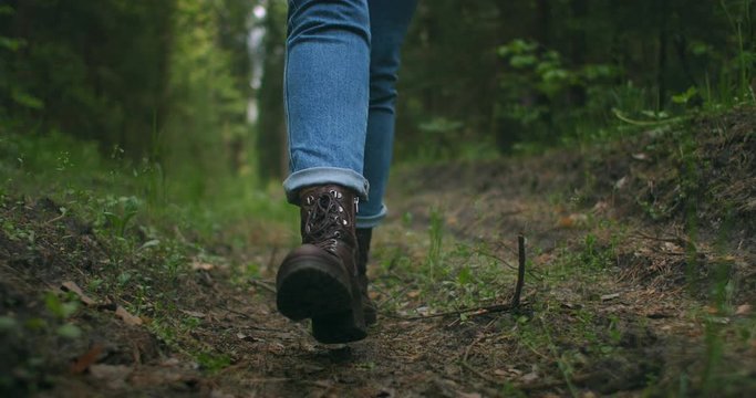 Close up of women legs hiking steep terrain in slow motion. Feet in Hiking Boots Walking on Autumn Road. woman feet tracking on fall day outdoors, walking through woodland