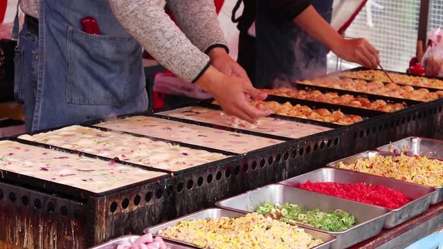 Close Up Japanese Man Making Traditional Takoyaki Balls At A Colorful Food Market Stall In Japan
