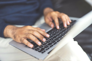 lifestyle man close up hand keyboard sit work on sofa using a laptop computer to work home and search information social network online.