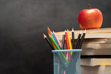 Back to school and education concept. Books with pencil holder on wooden table. blackboard in background.