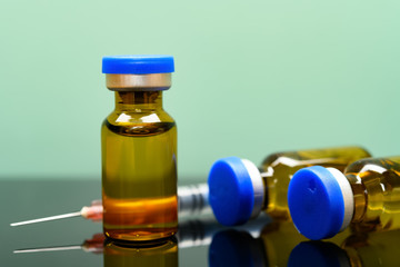 vaccine and syringe on a green background