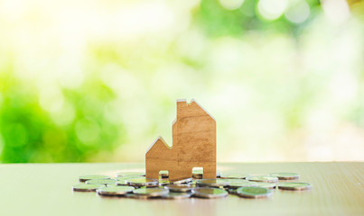 View of a pile of coins and house design on a green background, financial concepts, loading real estate with banking concepts, loans, property tax concepts.