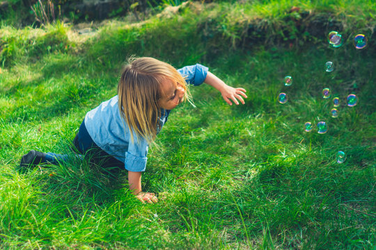 Preschooler on the grass catching bubbles