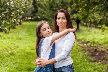 Fototapeta premium Portrait of little girl and beautiful mother in organic apple orchard happy and having fun.