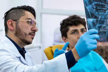 Male doctor showing an x-ray plate to his young male patient