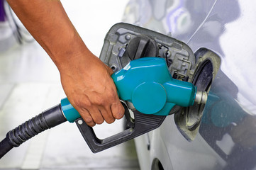 hand holding blue nozzle to fuel oil in  car