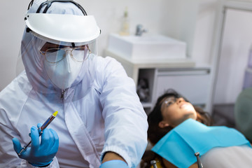 Dentist preparing anesthesia srynge to apply to young female patient