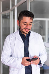 Young male doctor in his office using his smartphone
