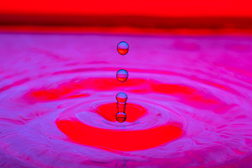water drop splash on color gradient red violet surface macro