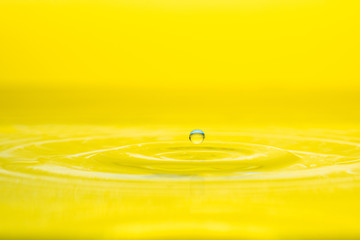 water drop splash on color gradient bright yellow surface macro