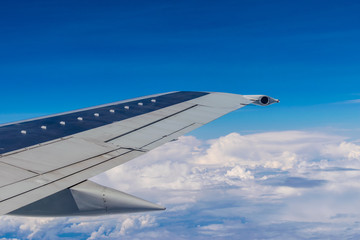 Obraz premium Wing of a plane flying above the clouds 
