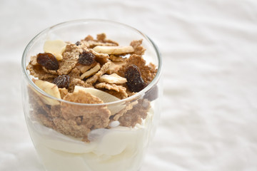 Greek yogurt with fruit and fiber cereal on a glass. The concept of healthy breakfast, healthy food, dietary plan and weight loss program. Selective focus. Copy space is on the right side.