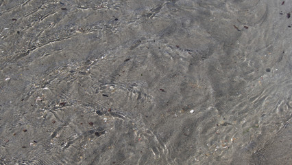 Sea water moving over a sandy beach on a warm sunny day