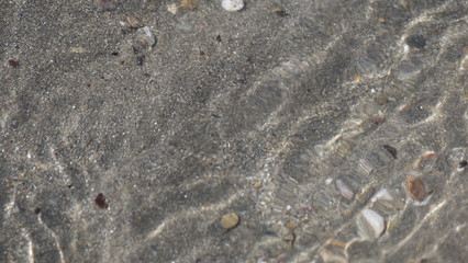 Sea water moving over a sandy beach on a warm sunny day