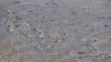 Sea water moving over a sandy beach on a warm sunny day