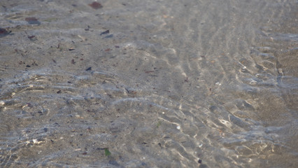 Sea water moving over a sandy beach on a warm sunny day