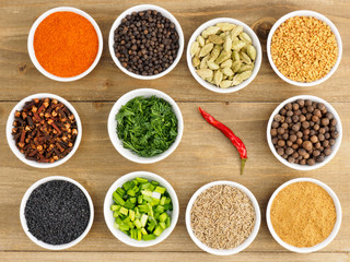 Spice set: red chili pepper, masala, black pepper, cumin, fenugreek, cloves, green cardamom, fennel, onion on wooden background. Healthy eating concept
