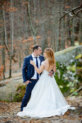 The bride and groom are hugging on the background of rocks.