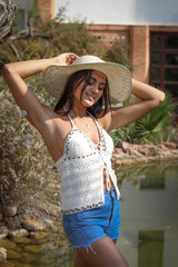 Summer time. Beautiful young brunette in a hat on a nature summer day.