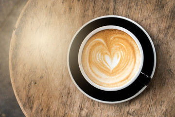 cup of cappuccino with heart-shaped foam in top, coffee on table in cafe