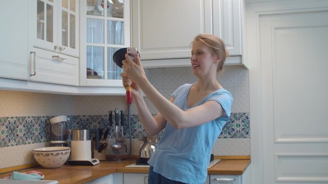 Happy young woman with a plunger in her hands taking a selfie and smiling. Kitchen sink clogging. Plumbing in need of repair. Housekeeping