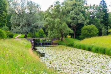 Black bridge-dam over the Slavyanka river in Pavlovsk park, Russia