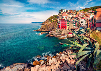 Fototapeta na wymiar Sunny summer cityscape of Riomaggiore, first city of Cique Terre sequence of hill cities. Bright morning view of Liguria, Italy, Europe. Mediterranean seascape. Traveling concept background.