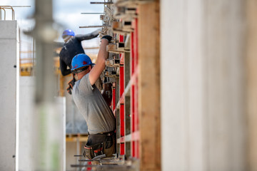 Male construction worker installing concrete retaining wall rebar on construction site