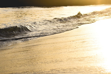 Sea water light splash on a sunset. Orange sun reflection na wet sand