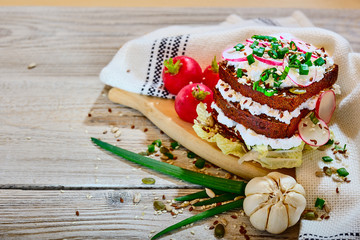Bruschetta with radish and cottage cheese on whole-grain brown bread with a lettuce leaf on a wooden background. Healthy food rustic style concept.