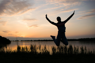 Fototapeta na wymiar A young woman is jumping, sunset as background. Freedom and happiness concept photography,