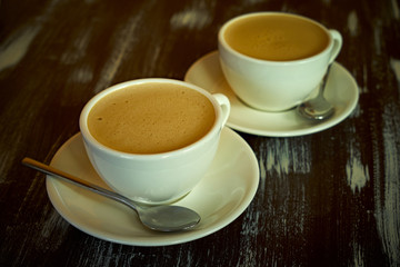 Two cups of coffee on a wooden table.