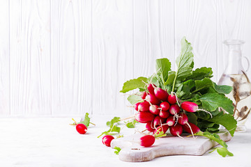 Spring harvest red radish on light background.  Bunch of fresh french breakfast radish. Growing vegetables. Vegetarian food.