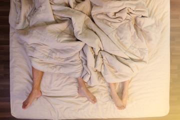 Close up of male and female feet sleeping on a bed in the bedroom.