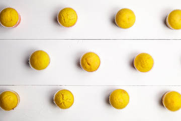 Cupcakes on white table, flat lay. Muffins on wooden background, homemade bakery
